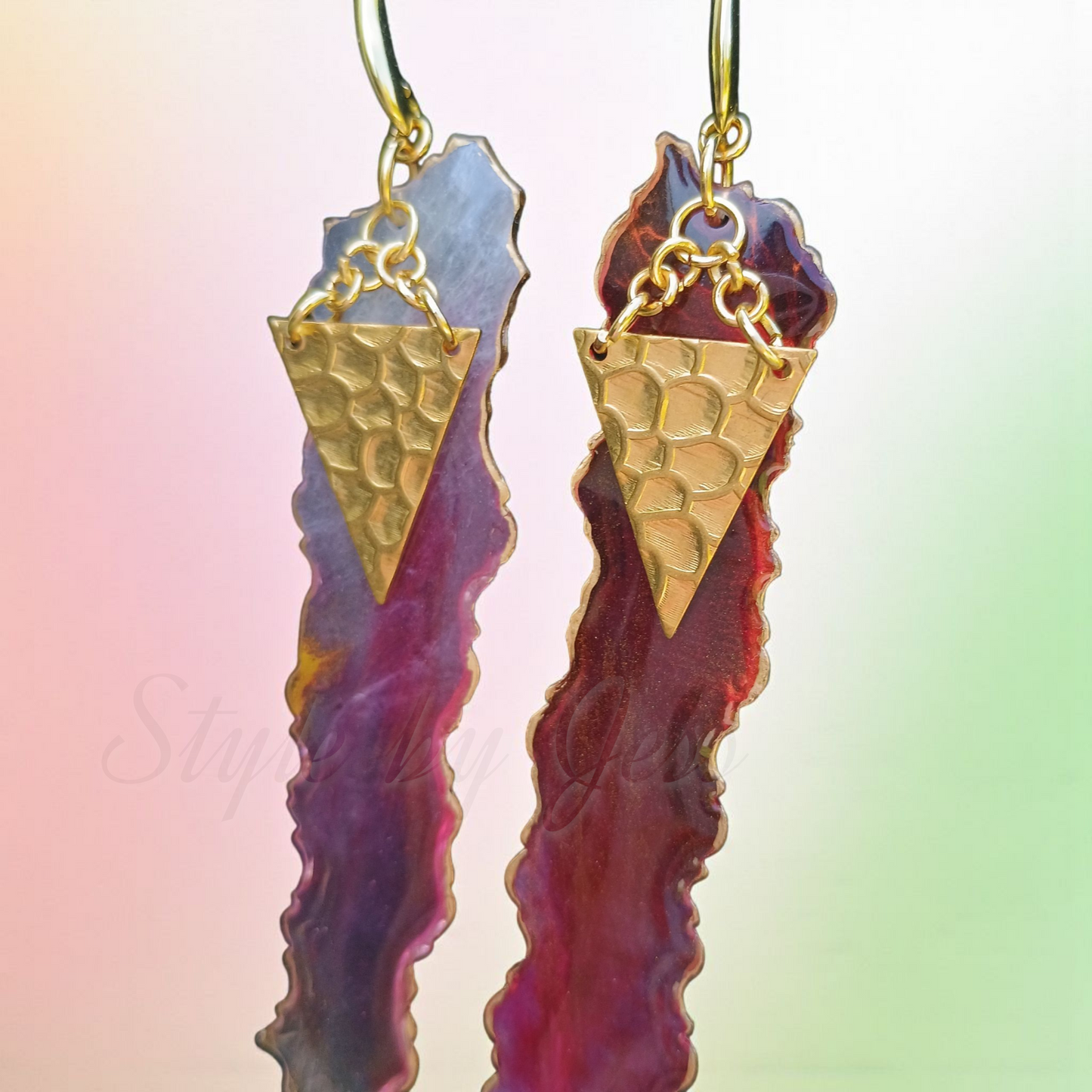 Gold and red geometric earrings on a colorful background