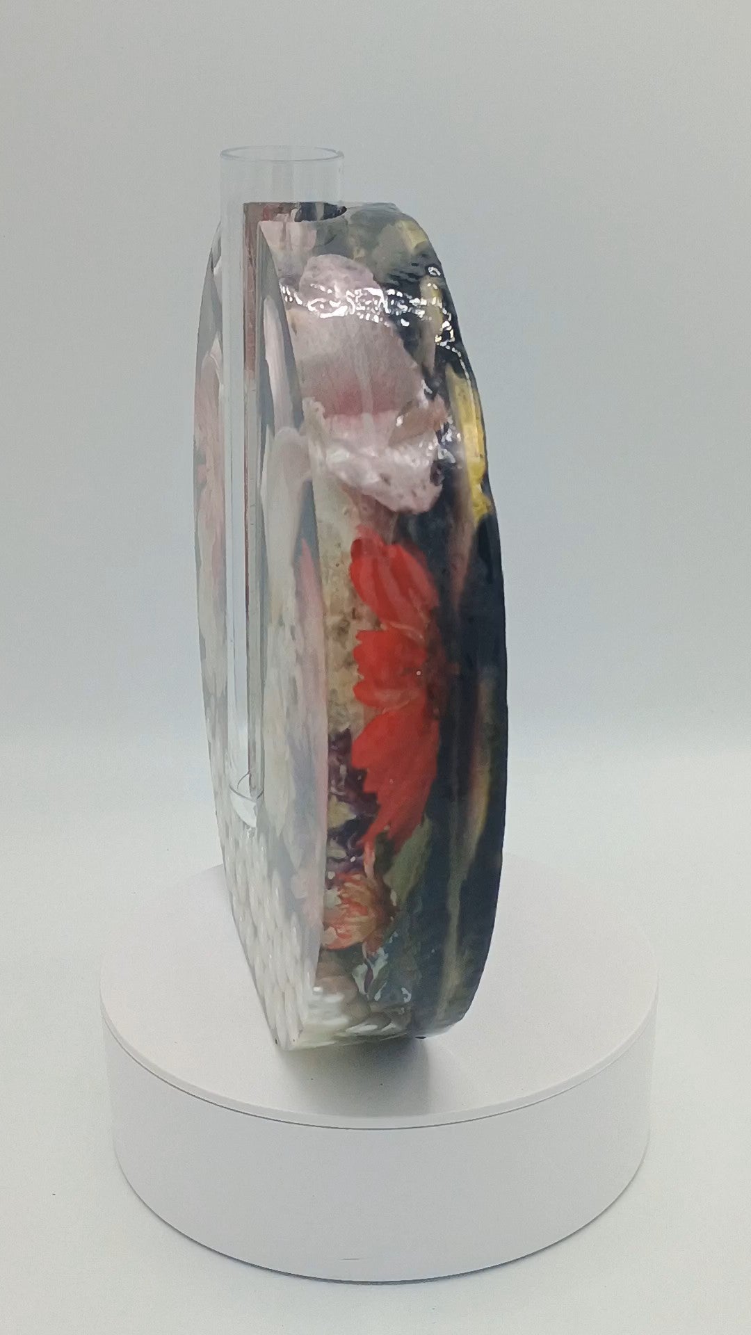 Glass vase with floral design on a white pedestal against a light gray background