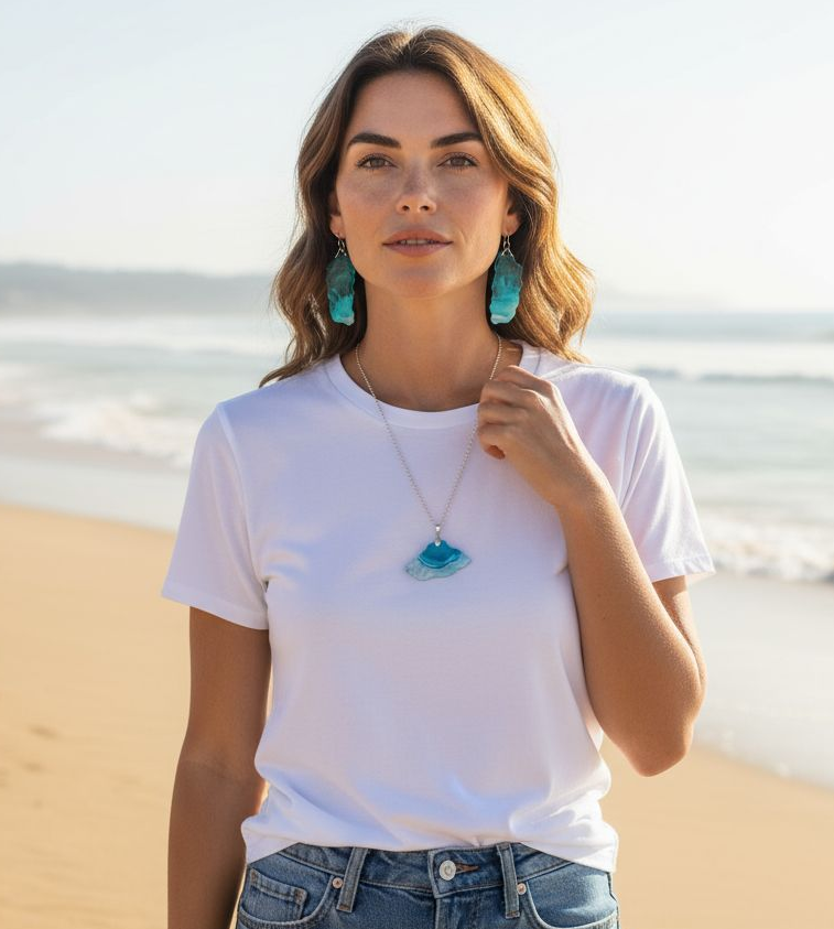 Woman on a beach wearing a white t-shirt, blue jeans, turquoise earrings, (beach wedding jewelry set) and a necklace a Style By Jess