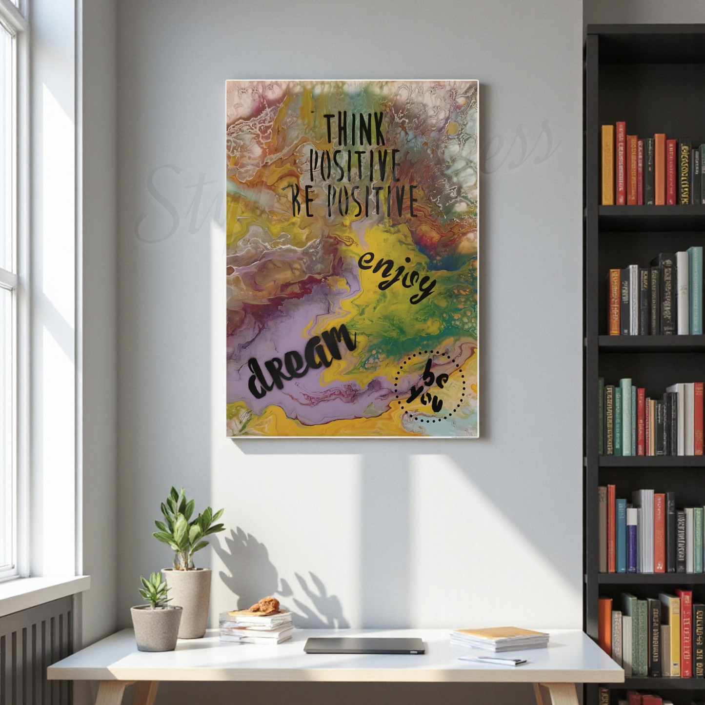 Colorful motivational poster on a wall above a desk with books and plants.