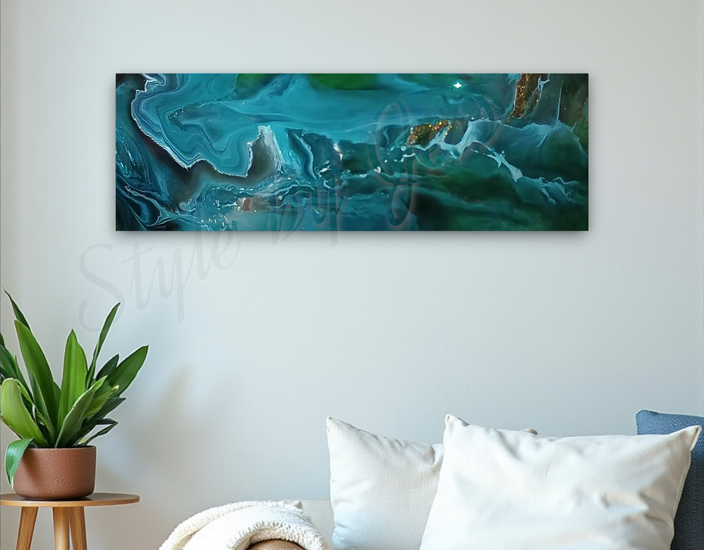 Abstract teal painting on a white wall above a sofa with cushions and a plant.