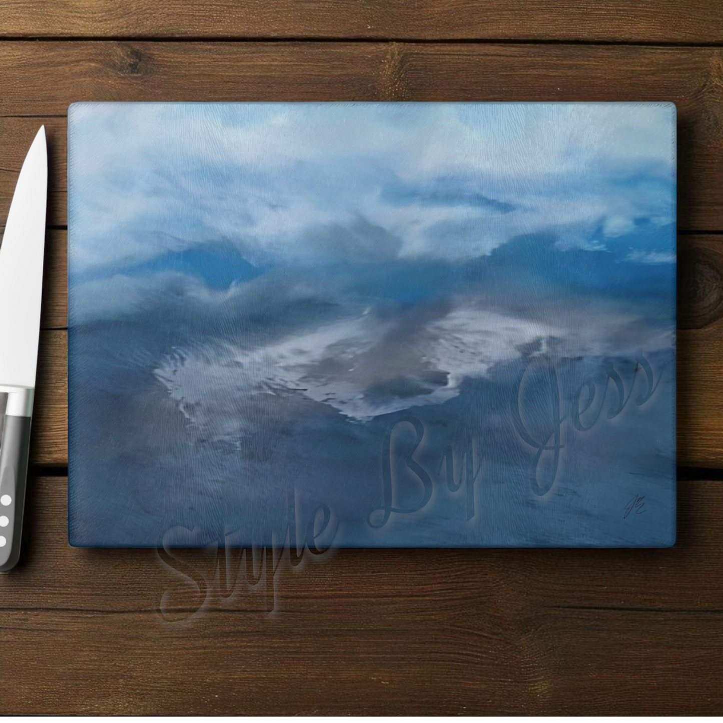 Chopping board with mountain design on a wooden surface next to a knife