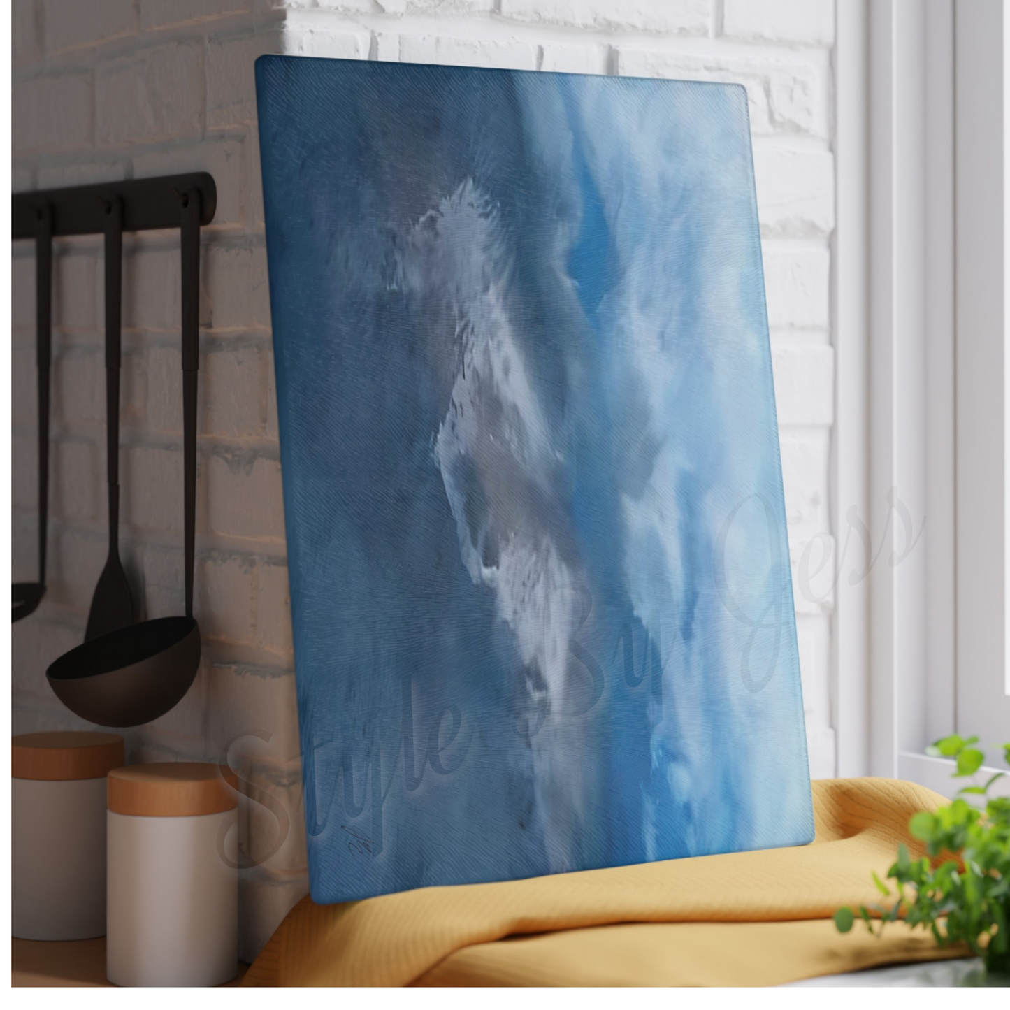 Blue abstract painting on a cutting board leaning against a white brick wall with kitchen utensils and decor.
