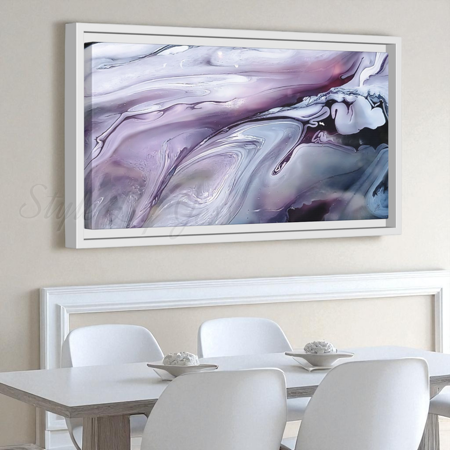 Abstract painting in a white frame on a wall above a dining table with chairs. Style By Jess