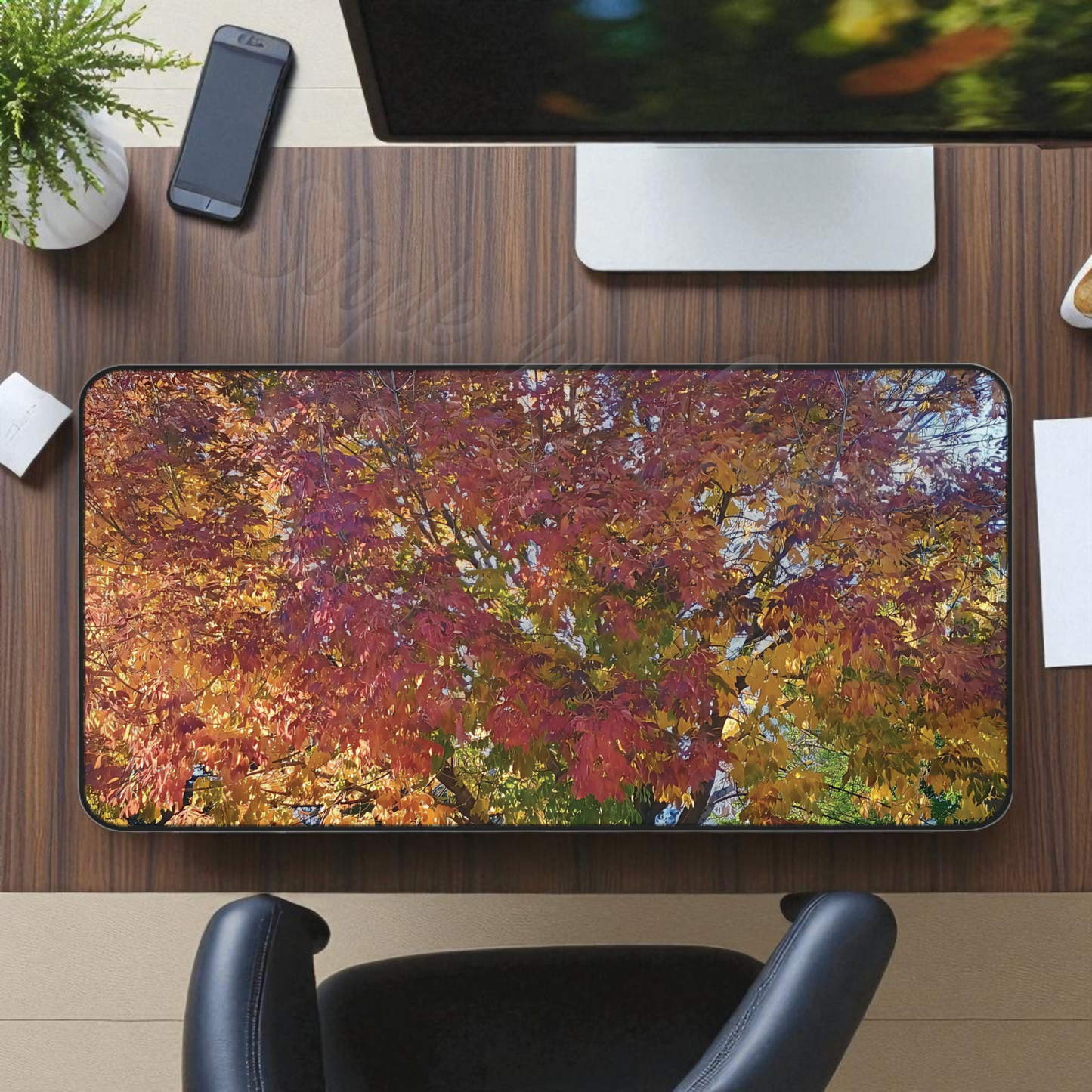 Desk setup with a colorful nature-themed mouse pad, phone, and computer monitor gift idea.