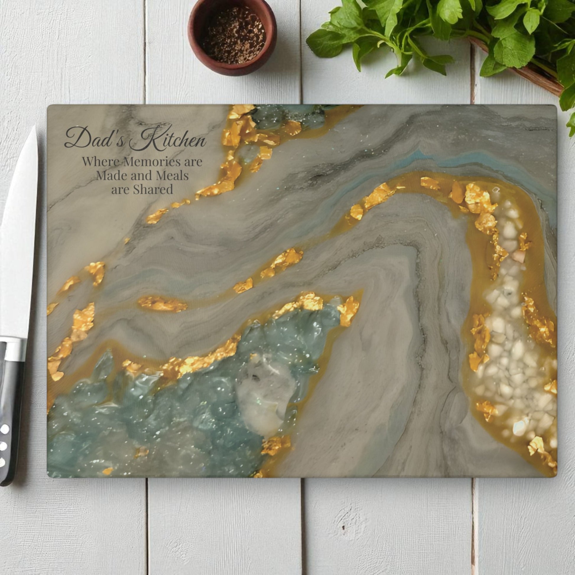 Marble-patterned cutting board with gold and white accents on a wooden surface. Dad's Kitchen Personalized Message