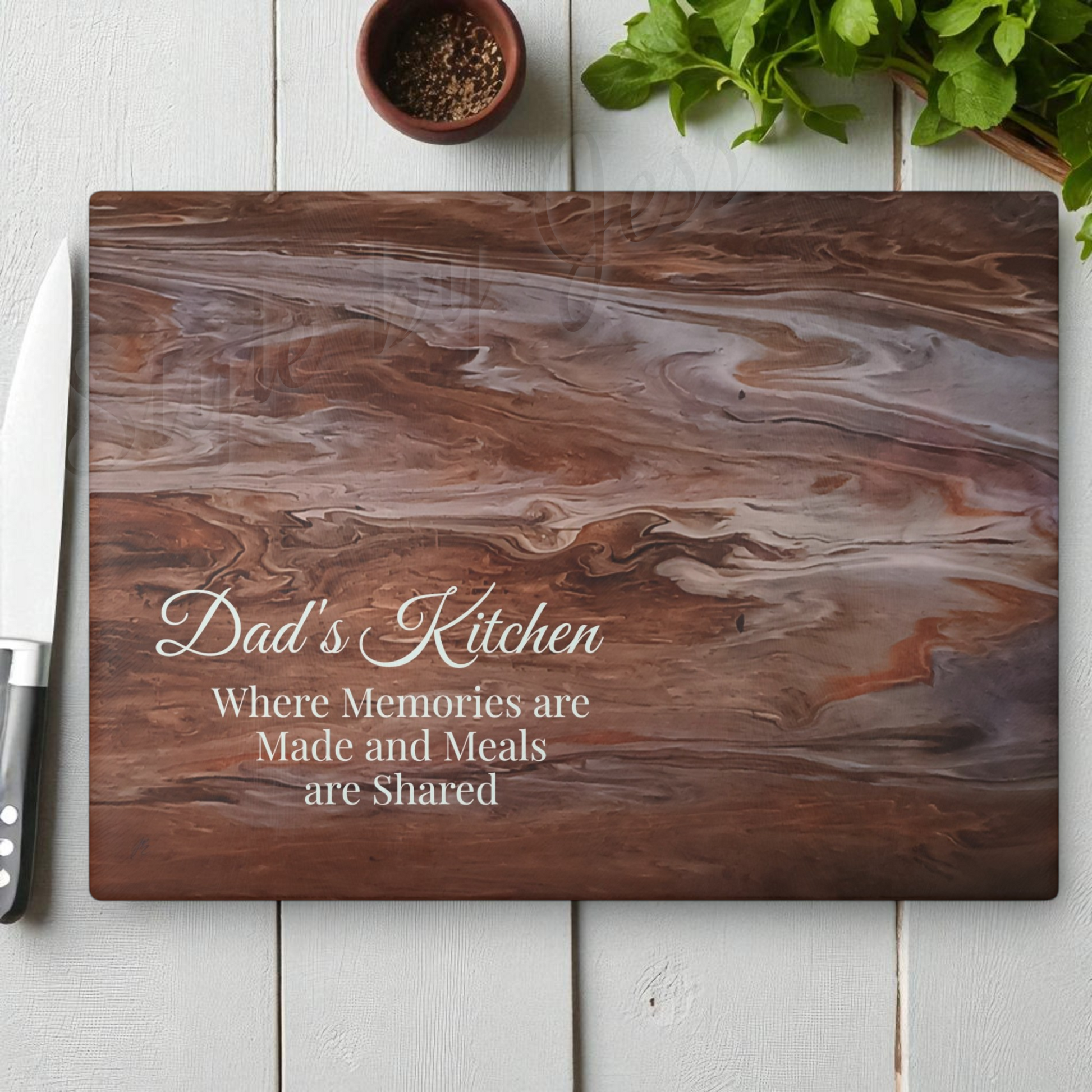 Wooden cutting board with 'Dad's Kitchen' text on a white surface with a knife and herbs. Style by Jess
